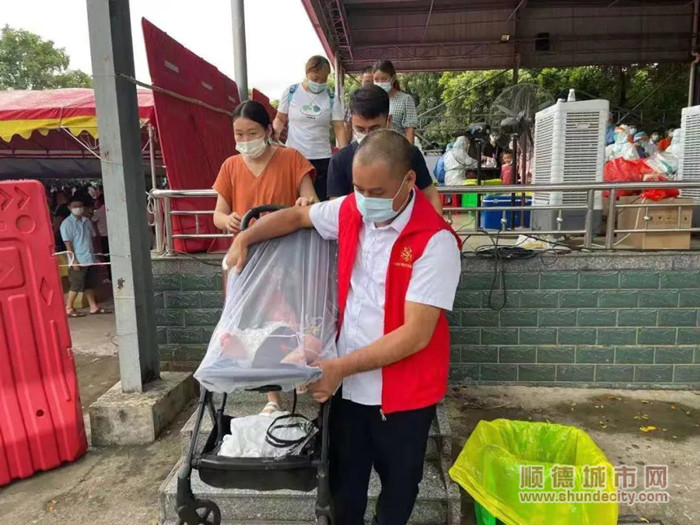 大闸社区检测点，一名母亲带着宝宝前来测核酸，一名志愿者帮助母亲运送婴儿车至安全地方。_副本.jpg