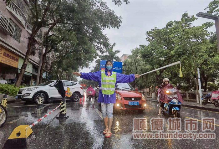 1.一位家长志愿者在雨中为孩子截停车流.jpg