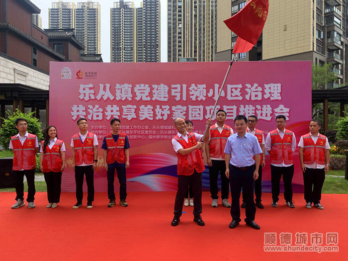 乐从镇党委副书记陈子荣（右）对乐从镇首个小区共治共享党群先锋队进行授旗。.jpg